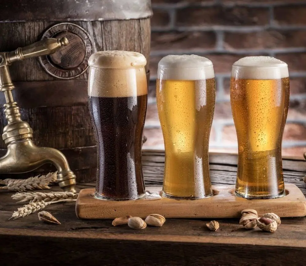 A wooden board with three different beers in it.